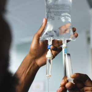 Close up of african american male doctor applying drip in hospital room. Medicine, healthcare, work and hospital.