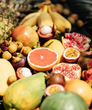 Fresh exotic fruits on green tropical palm leaves background - papaya, mango, pineapple, passion fruit, dragon fruit, watermelon. flat lay, overhead. Healthy food and diet concept. Top view.
