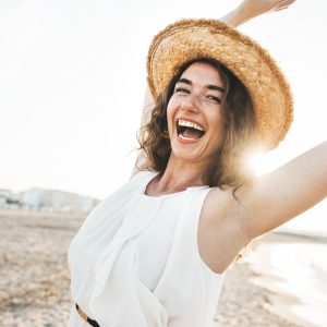 Happy beautiful young woman smiling at the beach side - Delightful girl enjoying sunny day out - Healthy lifestyle concept with female laughing outside
